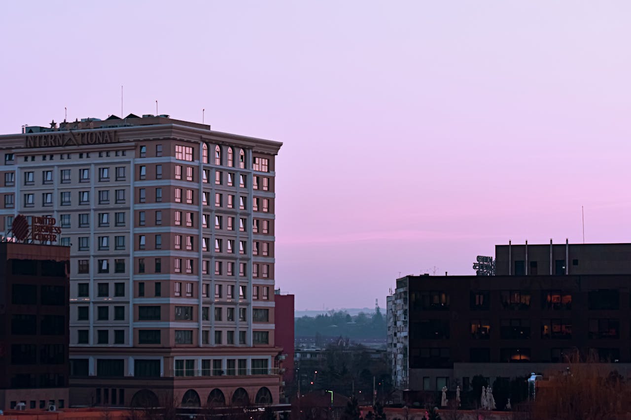 Cityscape view featuring modern buildings at twilight under a serene pink sky.